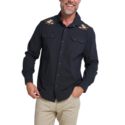 A smiling man wearing a howler dark navy western-style button-up shirt with embroidered eagle details on the shoulders and beige pants, photographed against a plain white background.