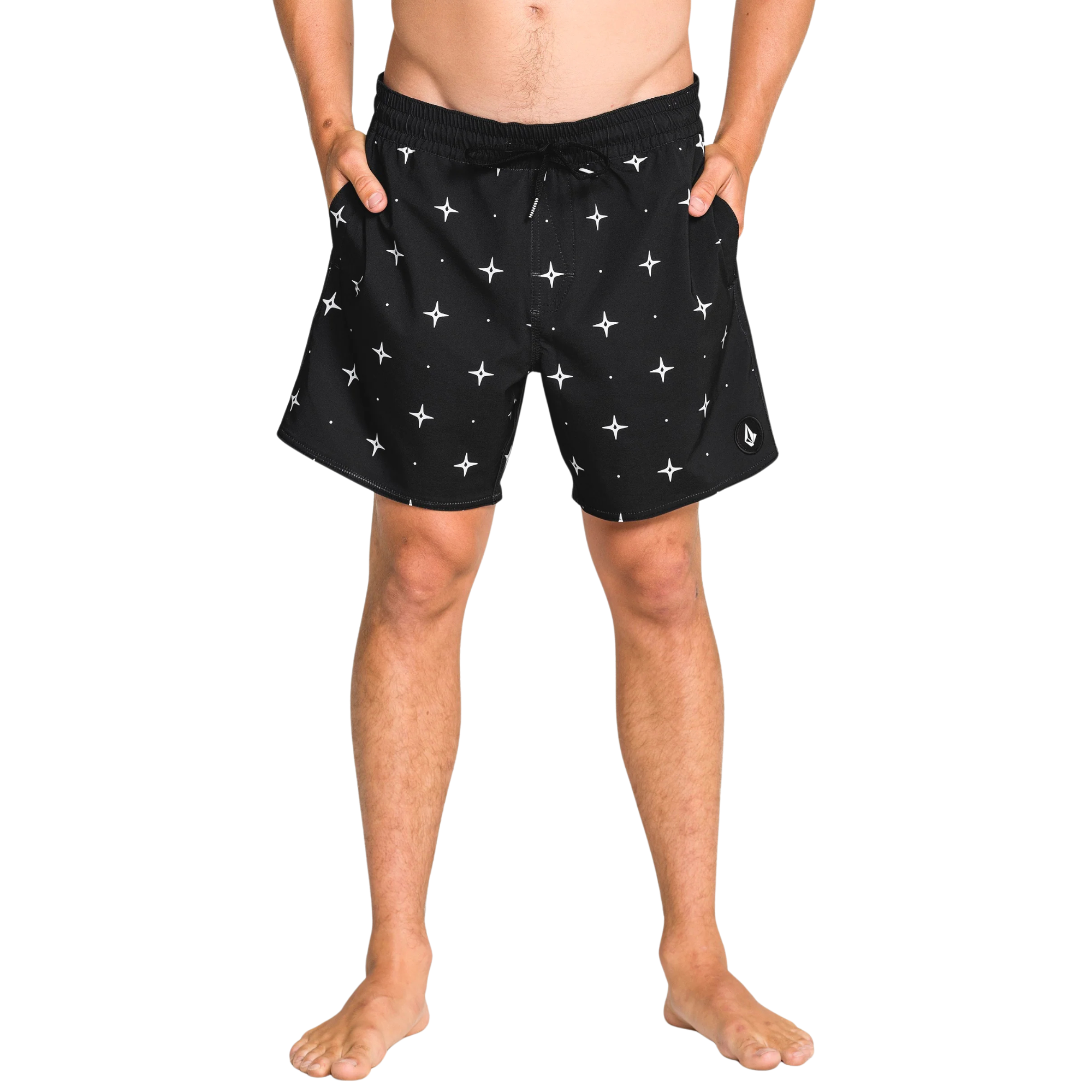 Man wearing black volcom lido swim shorts with star pattern on a white background