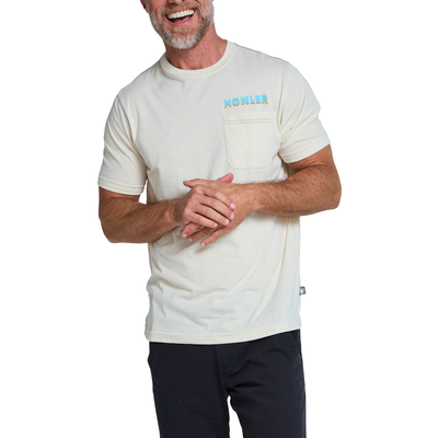 A man wearing a light cream-colored short-sleeve pocket t-shirt with a light blue 'HOWLER' logo on the chest, paired with dark pants, against a plain white background.