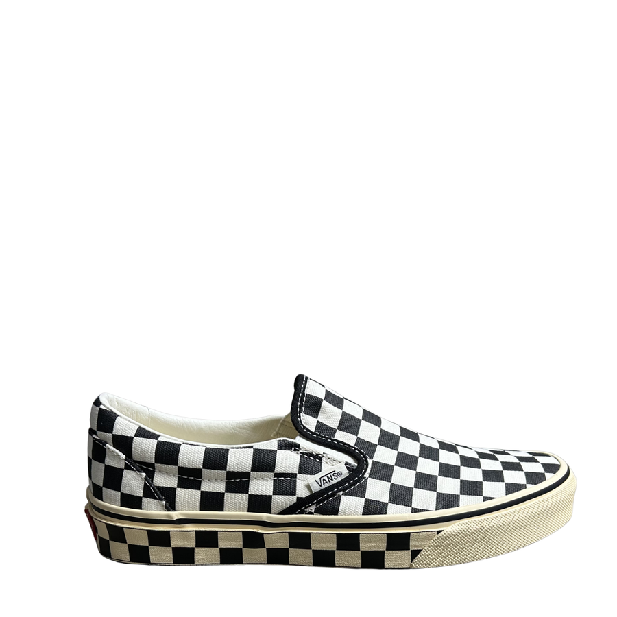 Black and white checkered slip-on Vans shoe with an off-white and black checkerboard sole on a white background