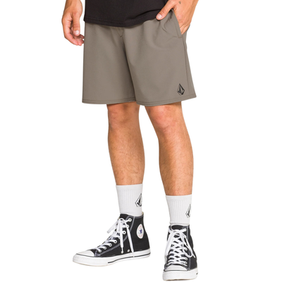 Man wearing a black tank top and TAN volcom nomaly elastic waist shorts on a white background
