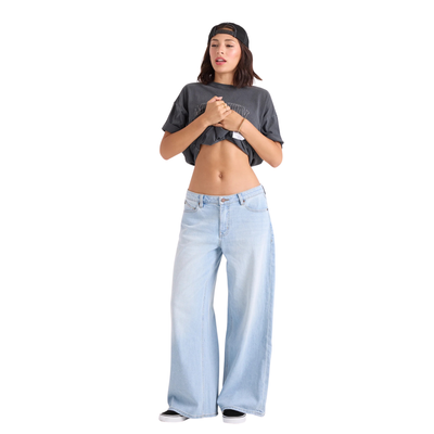 A woman in a black hat and black tee shirt wearing volcom stoned boyfriend low rise jeans on a white background